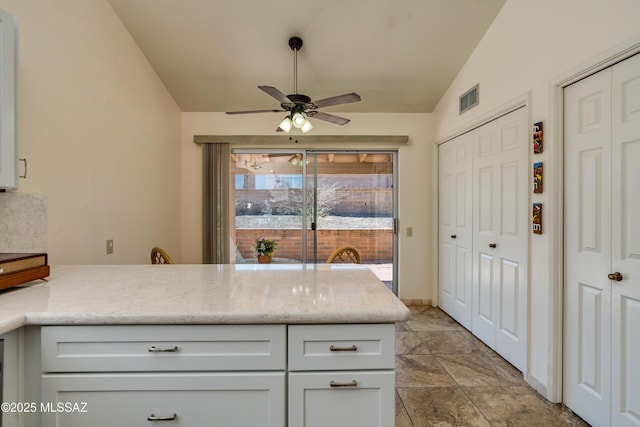 kitchen with light stone counters, a ceiling fan, visible vents, lofted ceiling, and a peninsula