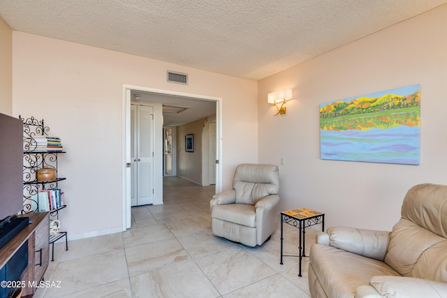 sitting room with visible vents, baseboards, and a textured ceiling