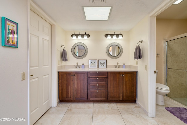 bathroom with double vanity, a stall shower, toilet, and a sink