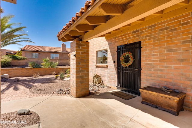 doorway to property with brick siding and a patio
