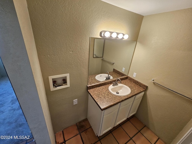 bathroom with tile patterned flooring, vanity, and a textured wall