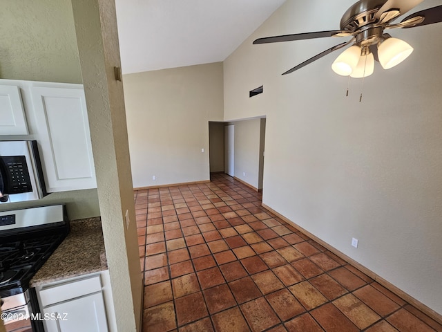 interior space with tile patterned floors, a textured wall, a ceiling fan, and vaulted ceiling