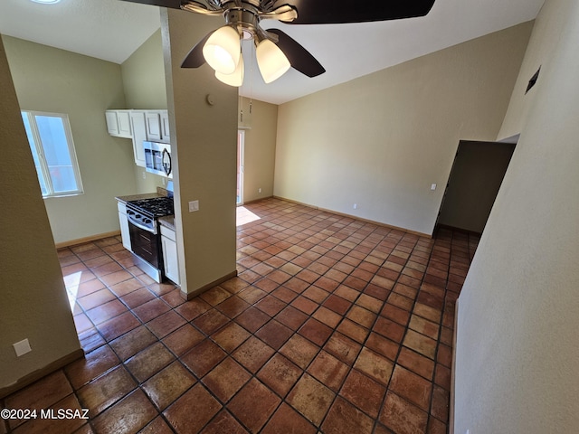interior space with tile patterned flooring, baseboards, appliances with stainless steel finishes, white cabinets, and a ceiling fan
