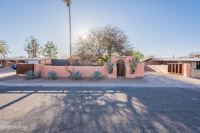view of front of property featuring a gate, a fenced front yard, and stucco siding