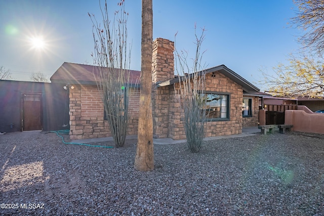 exterior space featuring stone siding and a chimney