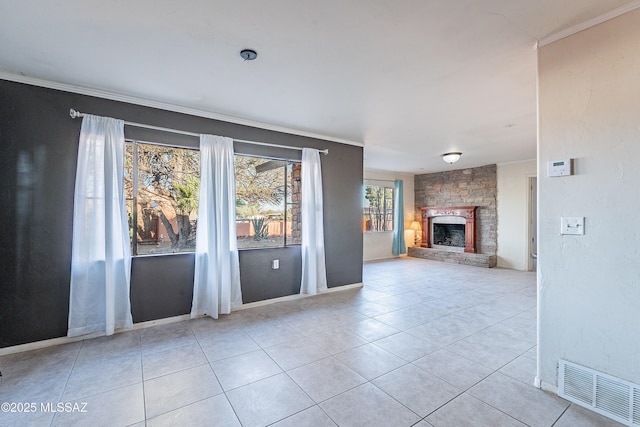unfurnished living room featuring a stone fireplace, tile patterned floors, crown molding, and visible vents