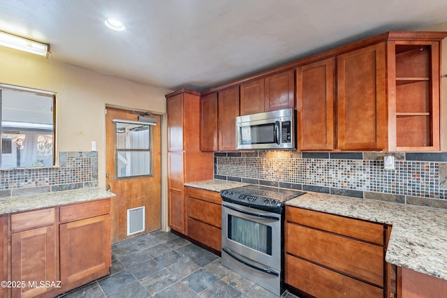 kitchen featuring light stone countertops, brown cabinetry, visible vents, appliances with stainless steel finishes, and tasteful backsplash