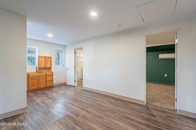 unfurnished bedroom featuring recessed lighting, baseboards, dark wood finished floors, and a wall unit AC