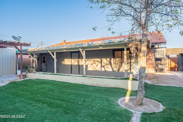 back of house featuring a lawn, a sunroom, and stucco siding