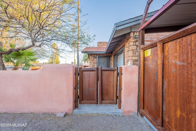 view of side of property featuring stone siding, fence, and a gate