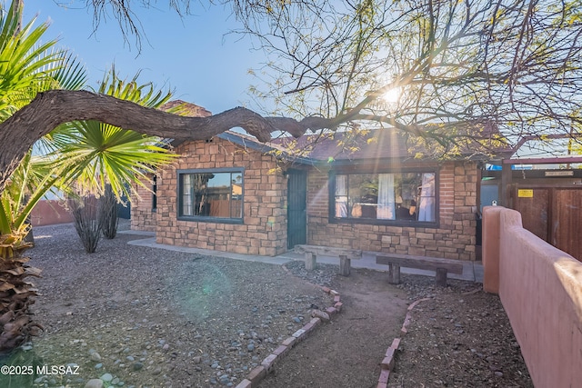 view of front of home featuring stone siding and fence