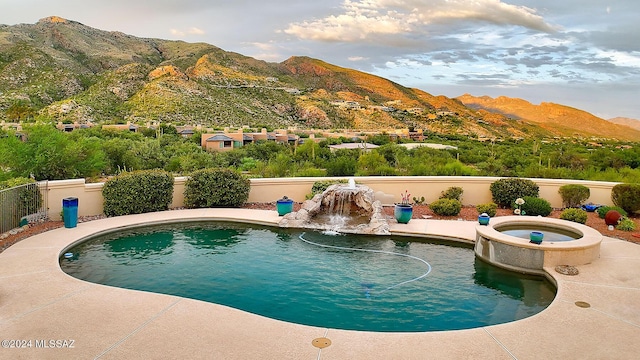 view of swimming pool with a fenced backyard, a mountain view, and a pool with connected hot tub
