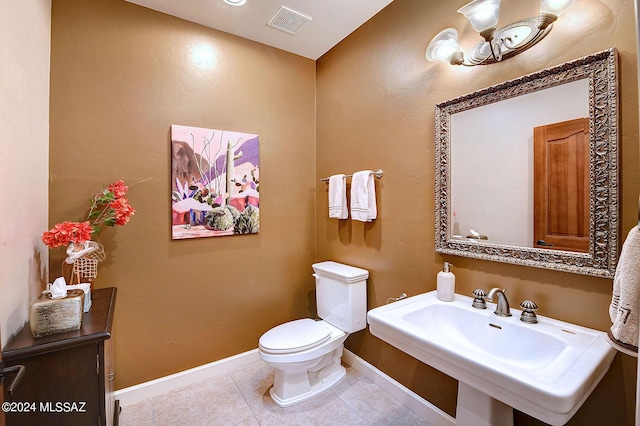 half bath featuring baseboards, visible vents, a sink, tile patterned floors, and toilet