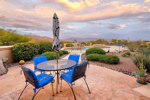 view of patio featuring outdoor dining space, fence, and a mountain view