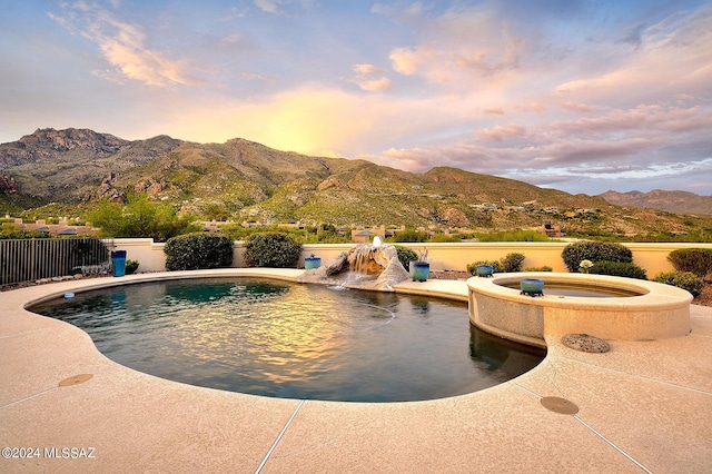view of swimming pool with an in ground hot tub, fence, and a mountain view