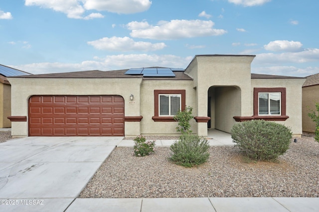 view of front of home with stucco siding, a garage, and solar panels