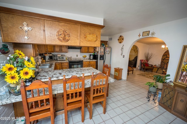 dining space featuring arched walkways, visible vents, a toaster, and light tile patterned flooring