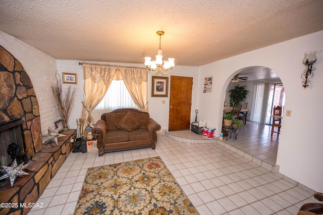 living area featuring arched walkways, a textured ceiling, an inviting chandelier, and light tile patterned floors