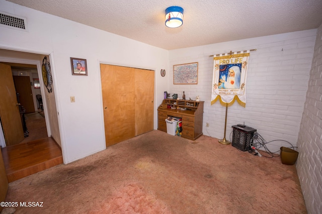 bedroom with a textured ceiling, visible vents, and carpet
