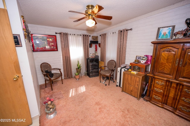 carpeted office space featuring a textured ceiling, ceiling fan, and brick wall