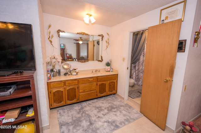 bathroom with a textured ceiling, toilet, ceiling fan, and vanity