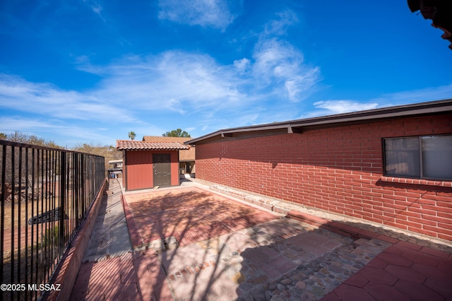 view of home's exterior with a patio, a tile roof, fence, and an outbuilding