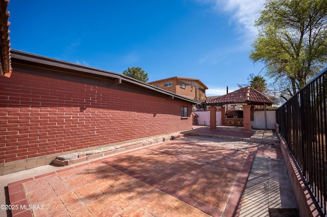 view of home's exterior with a patio, brick siding, a fenced backyard, and a gazebo