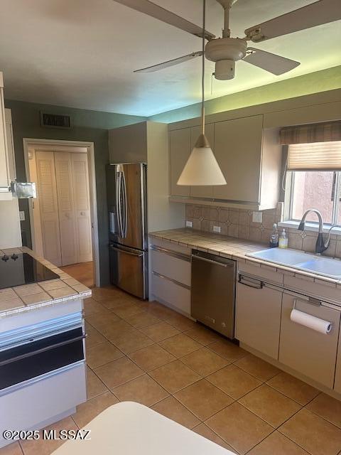 kitchen featuring a sink, tile counters, white cabinetry, tasteful backsplash, and stainless steel appliances