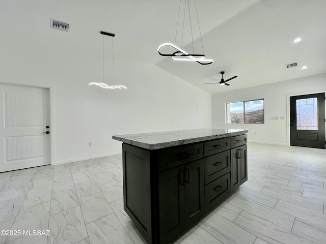 kitchen with marble finish floor, dark cabinetry, a center island, lofted ceiling, and ceiling fan