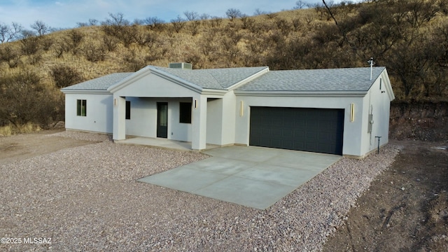view of front of property with cooling unit, roof with shingles, stucco siding, concrete driveway, and a garage