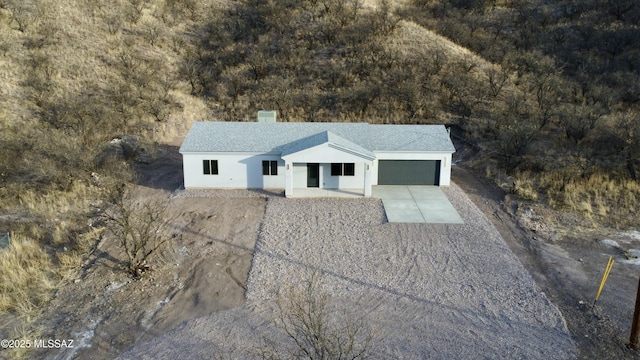 view of front of property featuring stucco siding, driveway, a chimney, and a garage