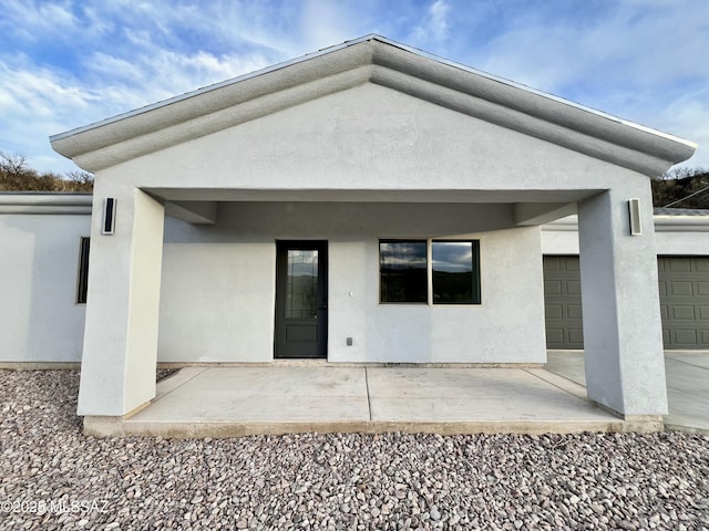 back of property with a patio area, stucco siding, and an attached garage