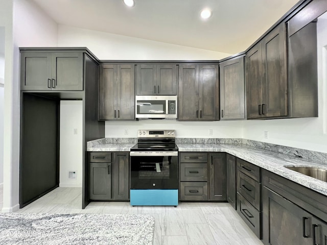 kitchen featuring dark brown cabinets, vaulted ceiling, light stone counters, recessed lighting, and stainless steel appliances