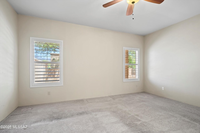 carpeted spare room with a ceiling fan and a wealth of natural light