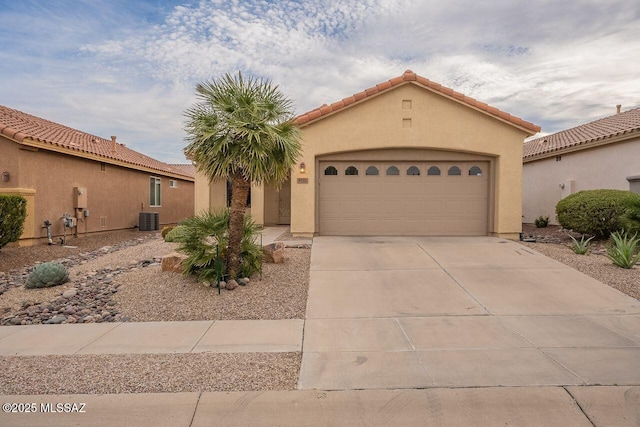 mediterranean / spanish home featuring concrete driveway, a garage, central AC, and stucco siding