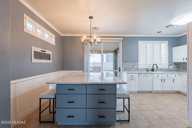kitchen with a breakfast bar area, visible vents, white dishwasher, ornamental molding, and white cabinetry