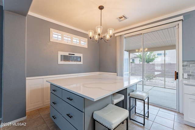 interior space with a notable chandelier, visible vents, light tile patterned floors, and wainscoting