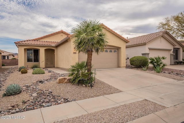 mediterranean / spanish-style home featuring stucco siding, driveway, a tile roof, and a garage