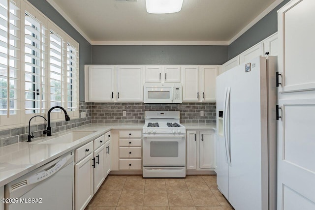 kitchen featuring white appliances, white cabinets, tasteful backsplash, and a sink