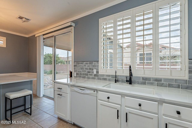 kitchen featuring tasteful backsplash, visible vents, white dishwasher, white cabinets, and a sink