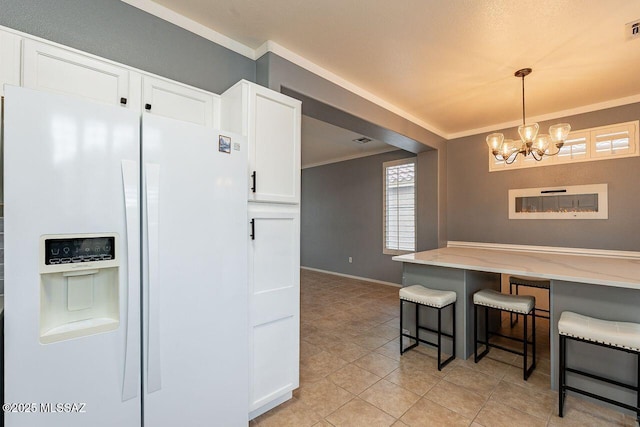 kitchen featuring a breakfast bar, white refrigerator with ice dispenser, white cabinetry, crown molding, and a chandelier
