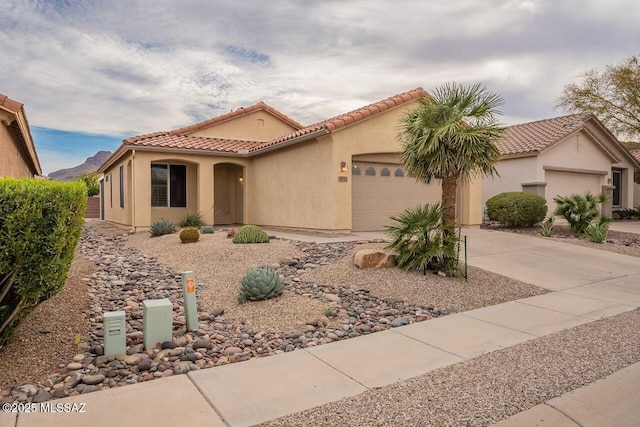 mediterranean / spanish home with a tiled roof, a garage, driveway, and stucco siding