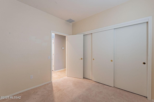 unfurnished bedroom with a closet, visible vents, light colored carpet, and baseboards