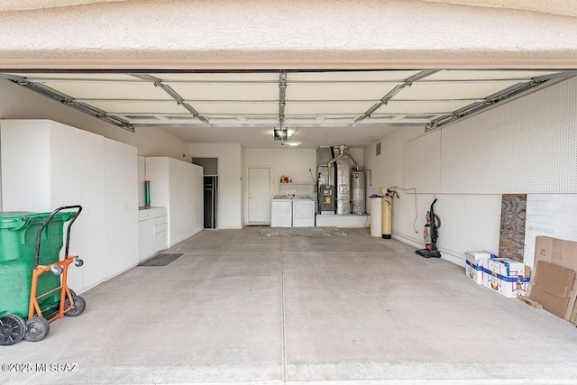 garage with water heater, a garage door opener, and separate washer and dryer