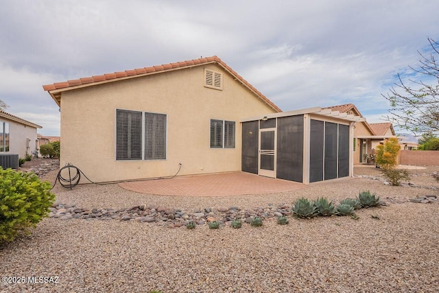 rear view of house with a patio, a sunroom, stucco siding, central air condition unit, and a tiled roof
