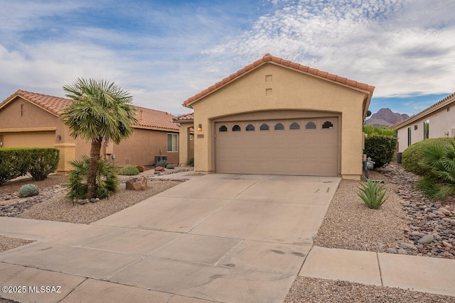 view of front of home with stucco siding, a garage, driveway, and a tiled roof