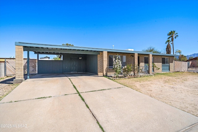 view of front facade with concrete driveway, brick siding, fence, and an attached carport