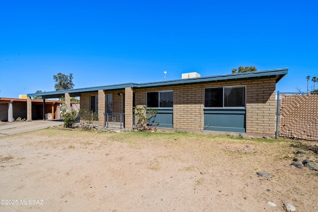 view of front of home with concrete driveway, brick siding, fence, and an attached carport