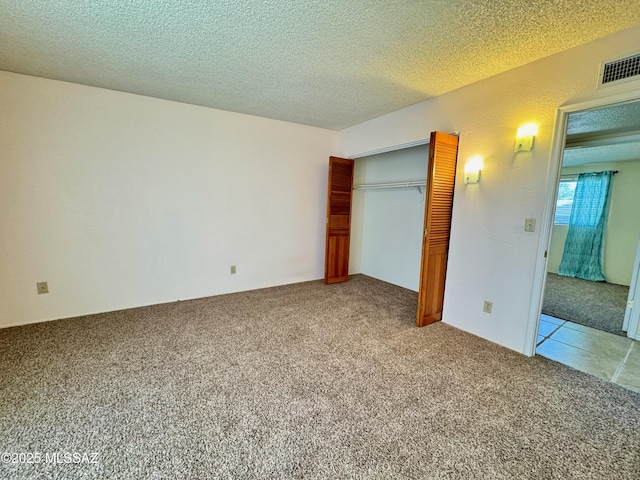 unfurnished bedroom with carpet floors, a textured ceiling, visible vents, and a closet