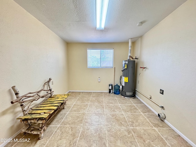 interior space with a textured ceiling, baseboards, and water heater